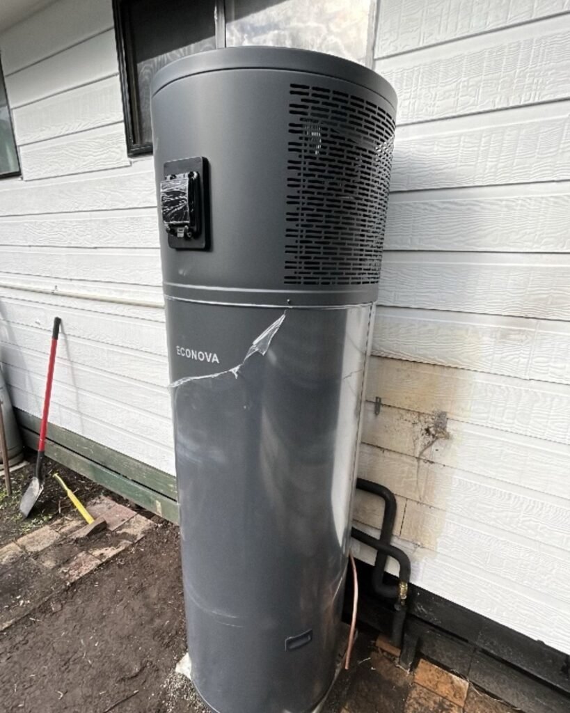Heat pump hot water system installed against a weatherboard wall